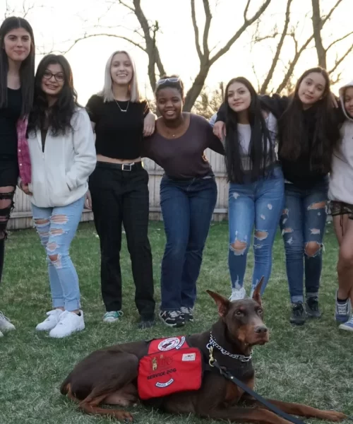 A group of girls and a dog posing for a picture